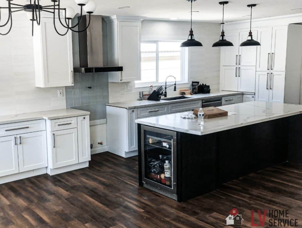 Spacious modern kitchen with white cabinets, a large island, and dark pendant lights.