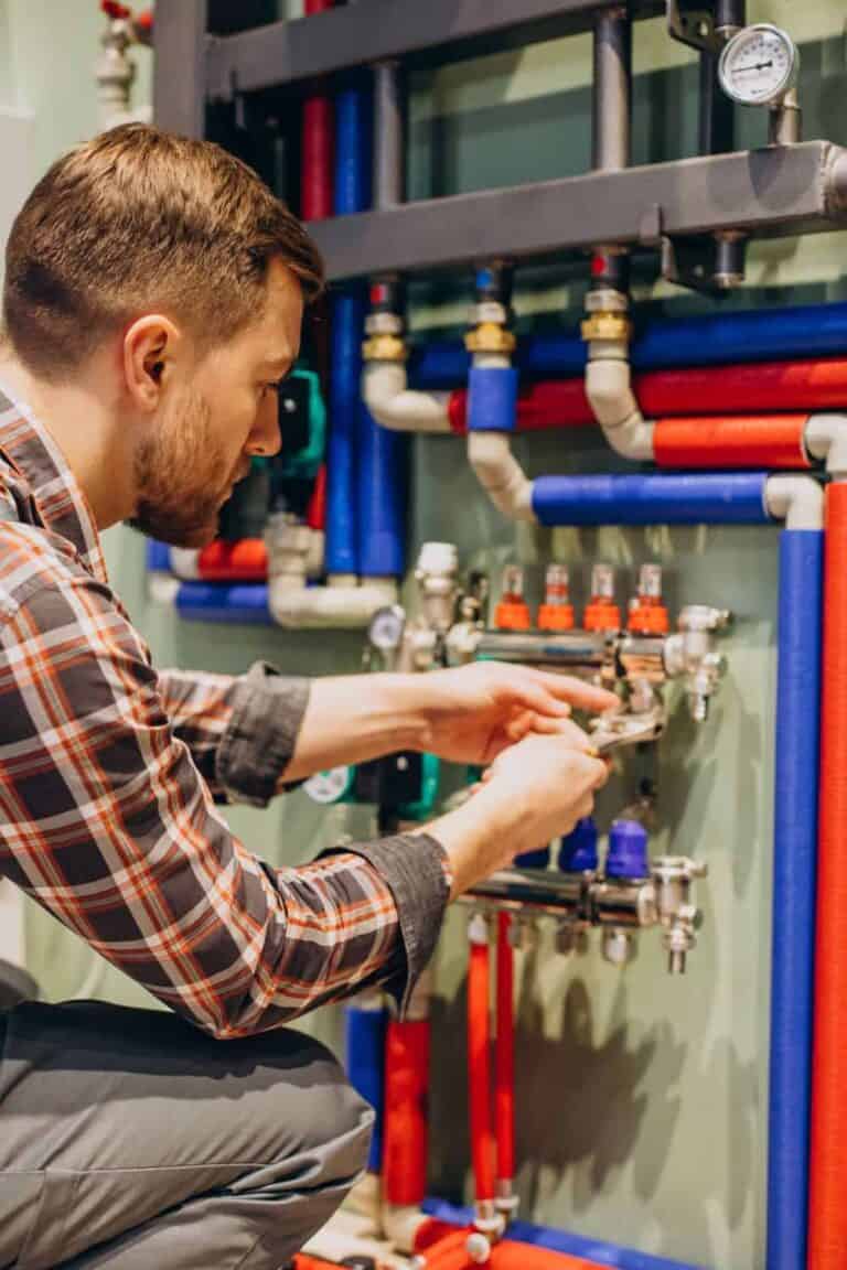 A man adjusting valves on a complex plumbing installation.